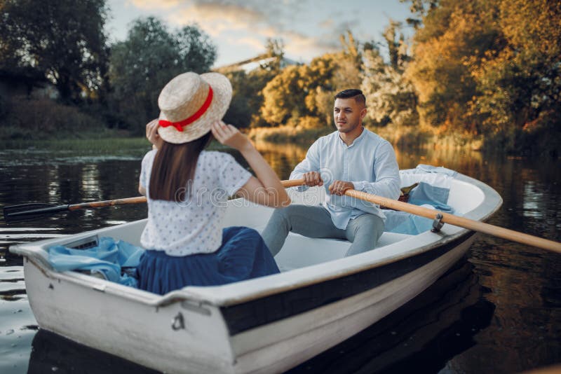 Love couple boating on lake at summer day. Romantic data, boat ride, men and women walking along the river. Love couple boating on lake at summer day. Romantic data, boat ride, men and women walking along the river