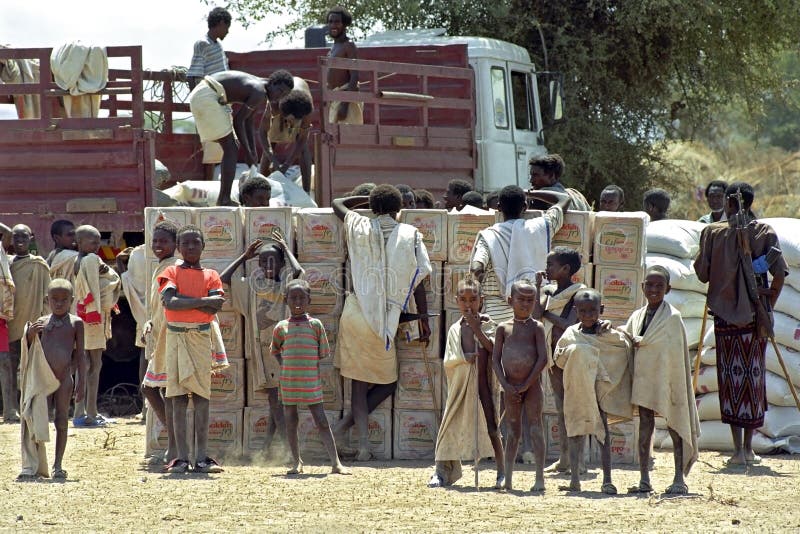 Ethiopia, Afar region: In Afar, an ethnic group of semi-nomadic livestock farmers, there is a threat of famine due to drought and massive death of their livestock. Employees and truck of the Red Cross, Comite International Geneve, deliver to a group Afar in the scorching heat of the Danakil Desert, a freight US wheat, food distribution, emergency aid. Red Cross staff and Afar men work peacefully together during the unloading of food, foodstuffs, USA wheat. People carrying, lugging, food supplies distributed by the Red Cross. Due to global warming and El Nino the region is plagued by persistent drought, droughts. A group of boys, children in traditional dress, shawl, stand for the food boxes, Golden Fry oil. Ethiopia, Afar region: In Afar, an ethnic group of semi-nomadic livestock farmers, there is a threat of famine due to drought and massive death of their livestock. Employees and truck of the Red Cross, Comite International Geneve, deliver to a group Afar in the scorching heat of the Danakil Desert, a freight US wheat, food distribution, emergency aid. Red Cross staff and Afar men work peacefully together during the unloading of food, foodstuffs, USA wheat. People carrying, lugging, food supplies distributed by the Red Cross. Due to global warming and El Nino the region is plagued by persistent drought, droughts. A group of boys, children in traditional dress, shawl, stand for the food boxes, Golden Fry oil.