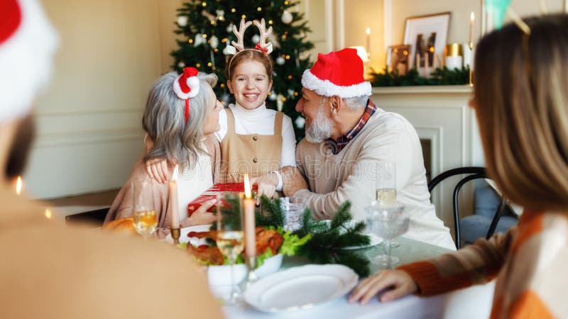 Liefhebbende grootouders geven kerstcadeau aan gelukkige kleindochter tijdens het feestmaal