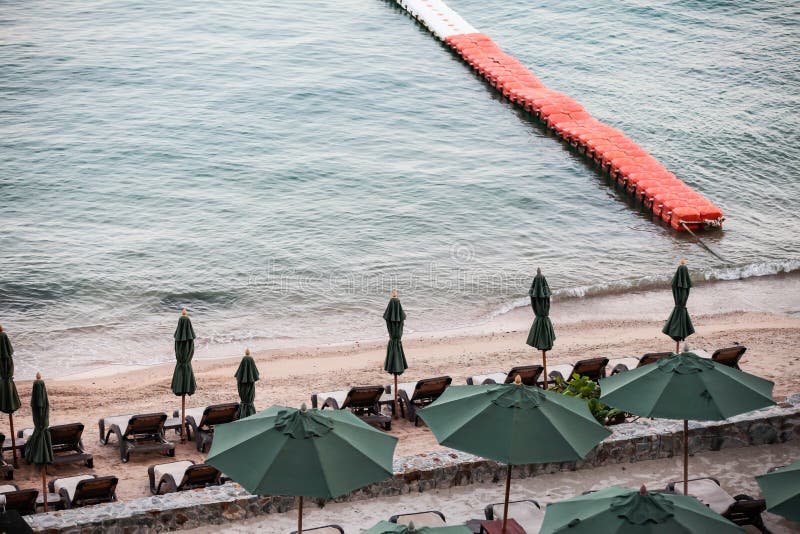 Liegestühle mit Sonnenschirm und Außenpool am Strand