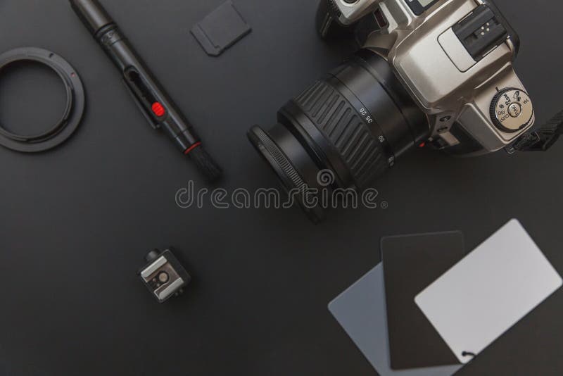 Lieu de travail de photographe avec la lentille de kit de caméra de système de caméra et appareil de l'accessoire de nettoyage de caméra sur le fond noir foncé de table. Concept de photographie de voyage de passe-temps. L'espace de copie étendu par appartement de vue de dessus