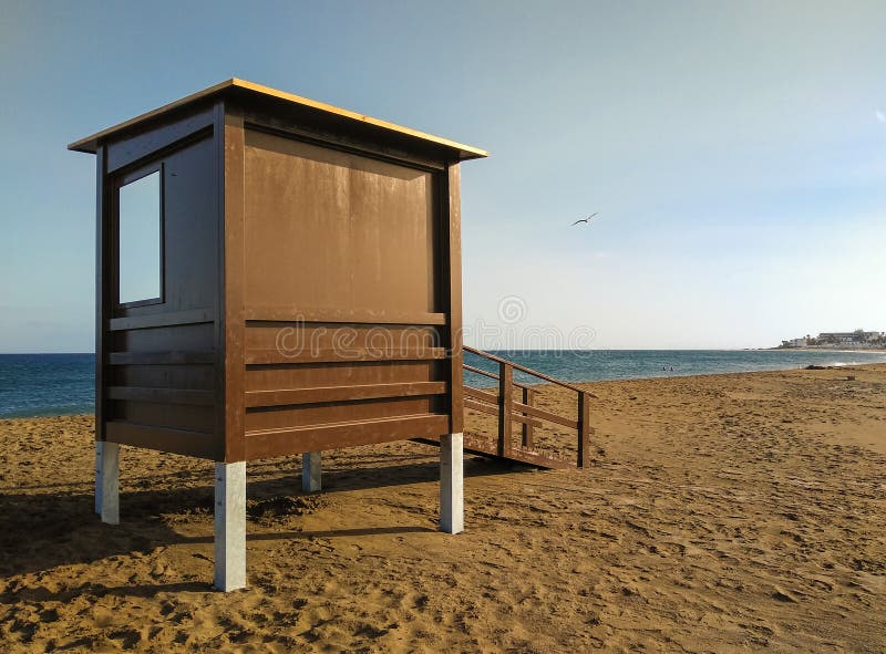 lifeguard house on the sand at a peaceful beach without guard or people swimming at the sunset hour. Behind the lifeguard station