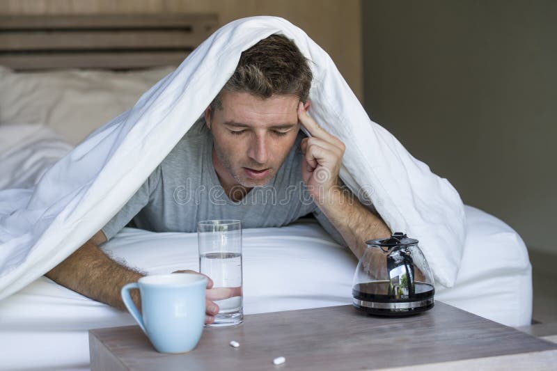 Lifestyle home portrait of young exhausted and wasted man waking up suffering headache and hangover after drinking alcohol at nigh royalty free stock photos Lifestyle home portrait of young exhausted and wasted man waking up suffering headache and hangover after drinking alcohol at nigh royalty free stock photos