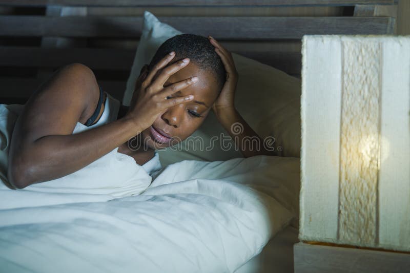 Lifestyle night portrait of young sad and stressed black african American woman lying on bed upset trying to sleep suffering insom royalty free stock photos Lifestyle night portrait of young sad and stressed black african American woman lying on bed upset trying to sleep suffering insom royalty free stock photos