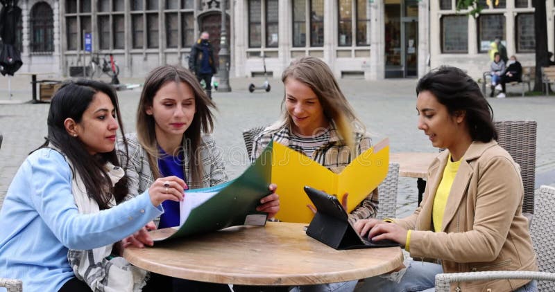 Lifestyle portrait of a diverse multiethnic group of four young smiling businesswomen with smartphones, notes and