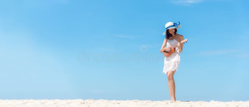 Lifestyle young woman relax on the summer beach.  Asia tourism people  playing guitar on beach in holiday, blue sky background.