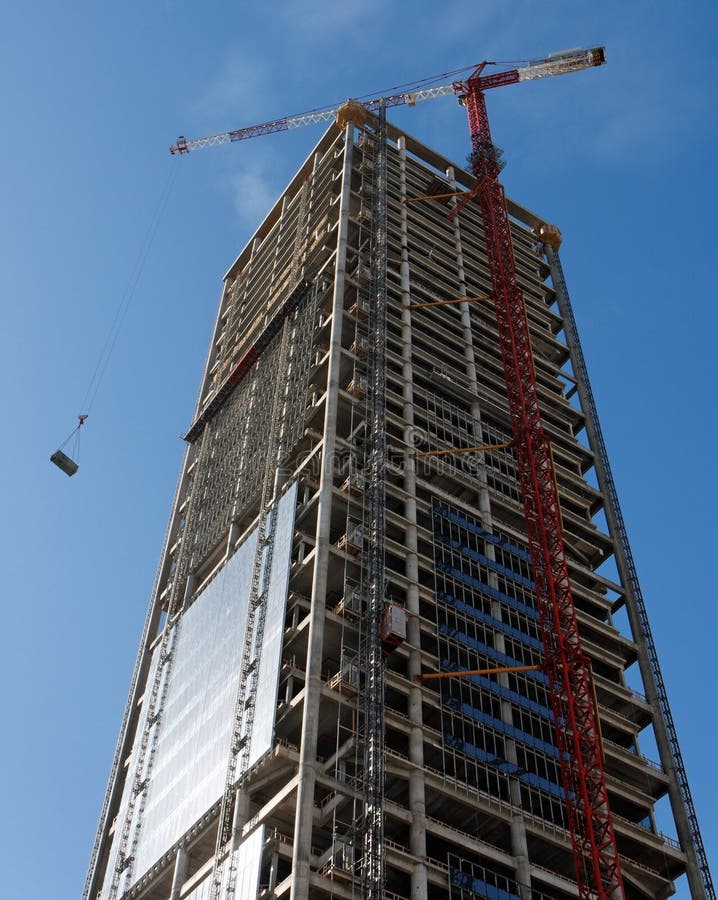 Lifting crane hoisting a weight at skyscraper cons