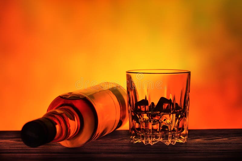Liggande flaska och ett exponeringsglas av whisky med is arkivbild Liggande flaska och ett exponeringsglas av whisky med is arkivbild