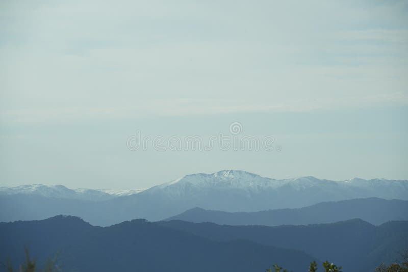 Light blue sky with clouds over snowy mountains landscape