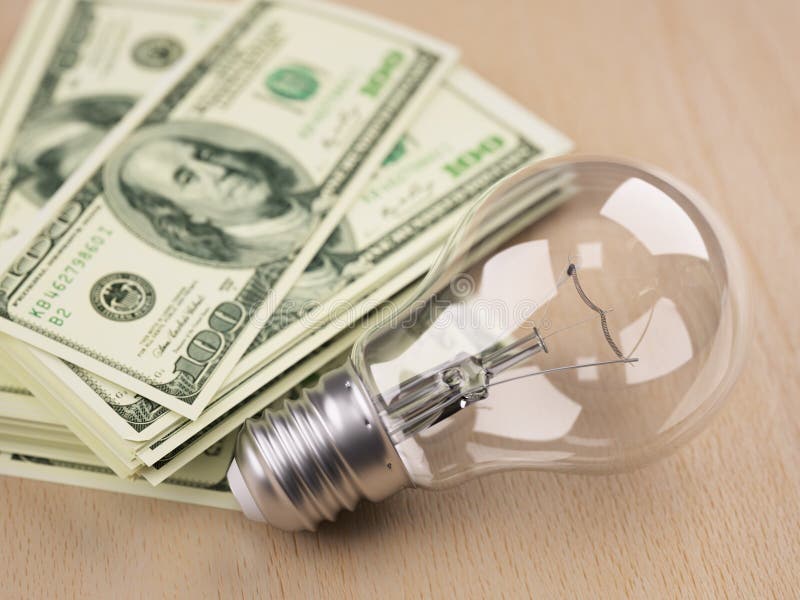 Light bulb in front of dollar bill stack royalty free stock photos