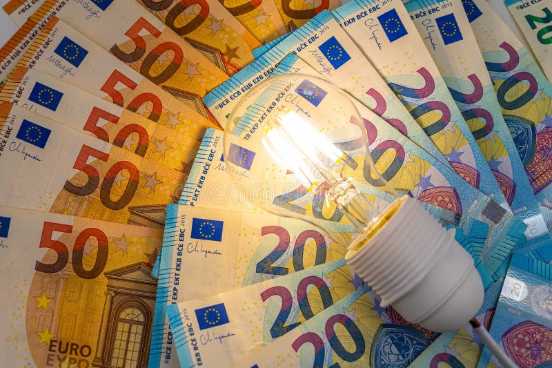 Light bulb on, on top of banknotes. stock image