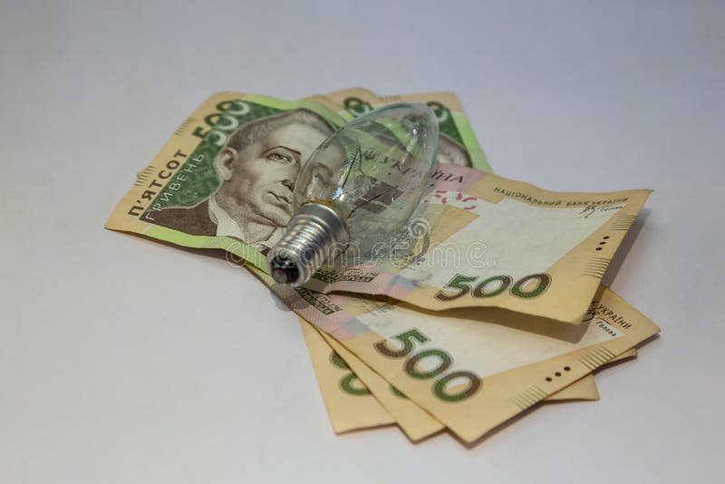 Light Bulb and Money on White Background. Energy Saving Stock Photo