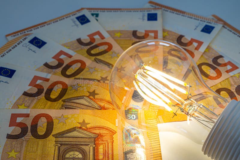 Light bulb on, on top of banknotes. stock image