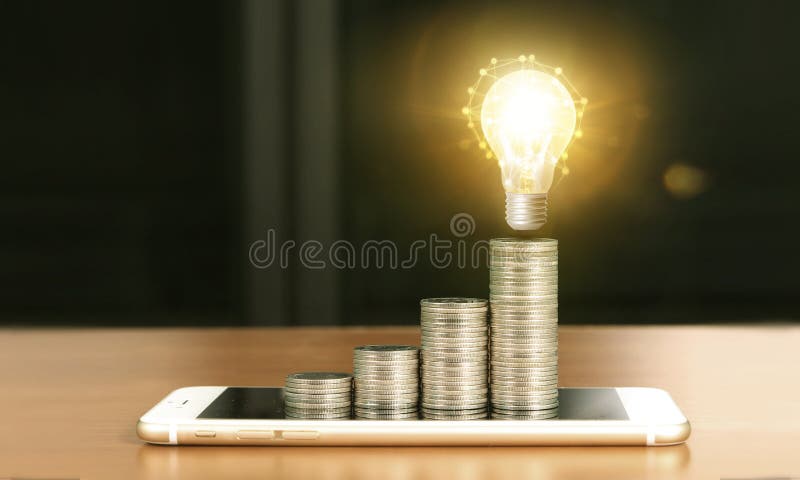 Light bulb on top of coins and smartphone stock photos