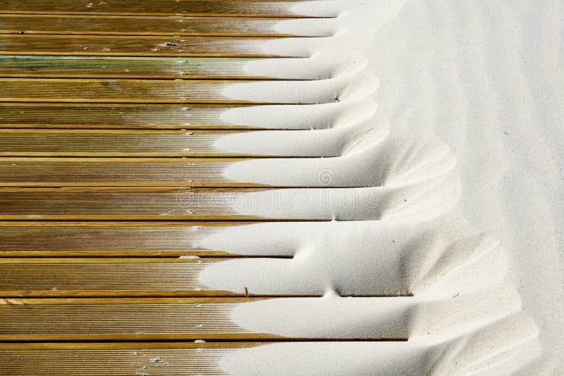 Light fine beach sand brought by the wind on brown outdoor terrace boards stock photos