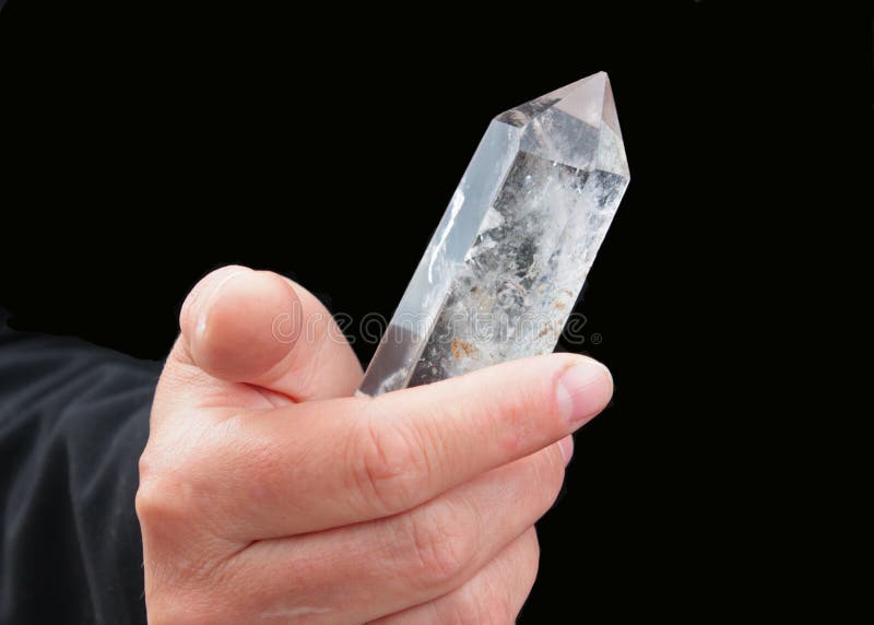 The rock crystal crystal is shone in a hand. The dark background is chosen. The rock crystal crystal is shone in a hand. The dark background is chosen.