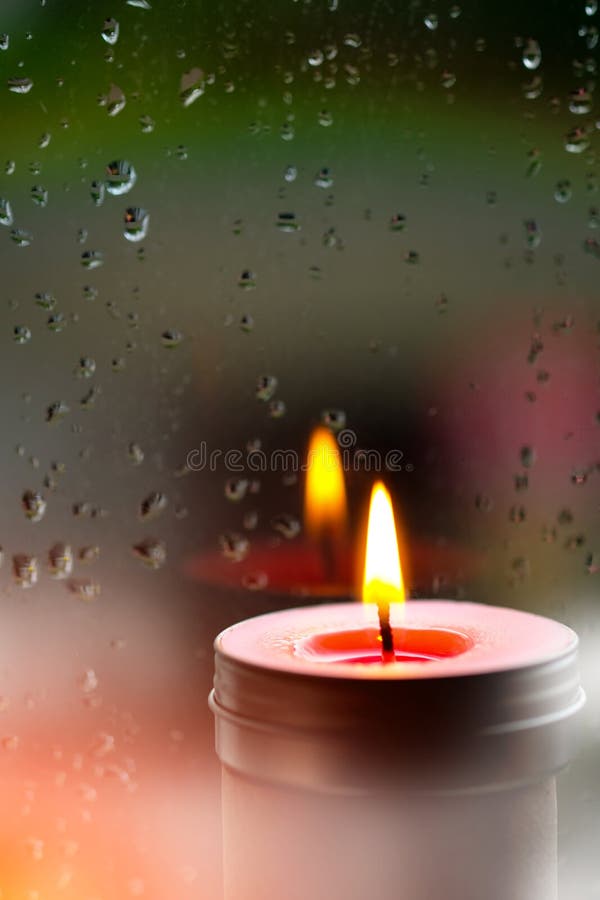 Light of Pink Candle in the Front at Window with Blurred Rain Dr Stock