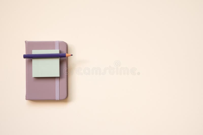 Light purple diary notebook and notepad, colored pencil on pink desk background. top view, copy space. studio shot