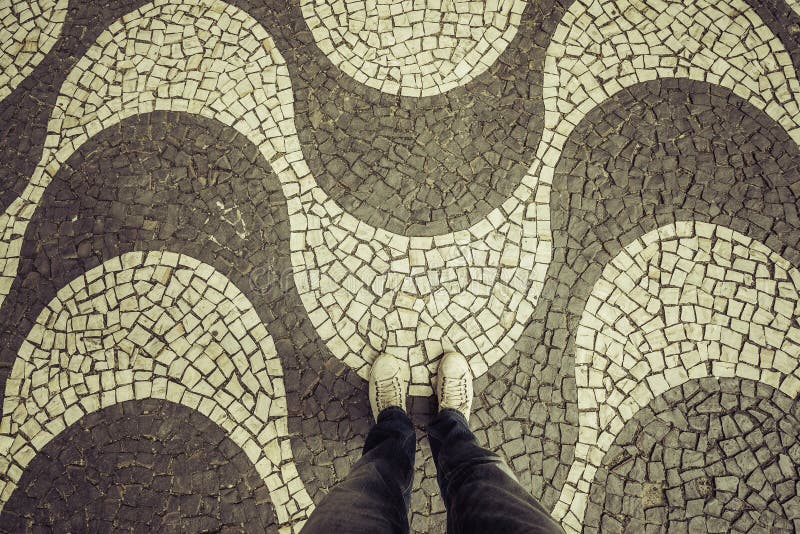Light Sneakers shoes walking on Copacabana mosaic sidewalk top view