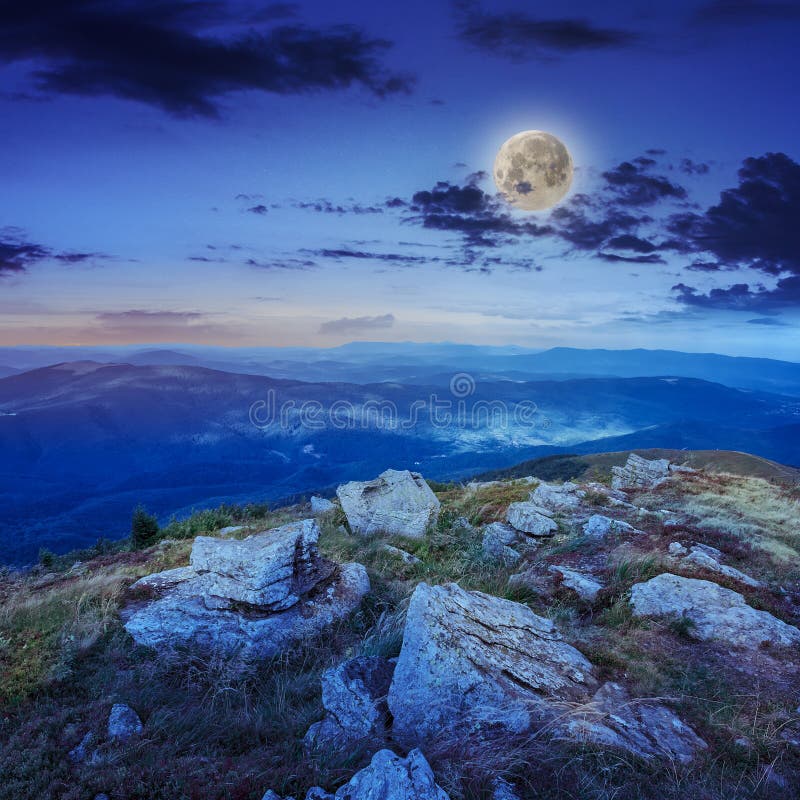 Light on stone mountain slope with forest at night