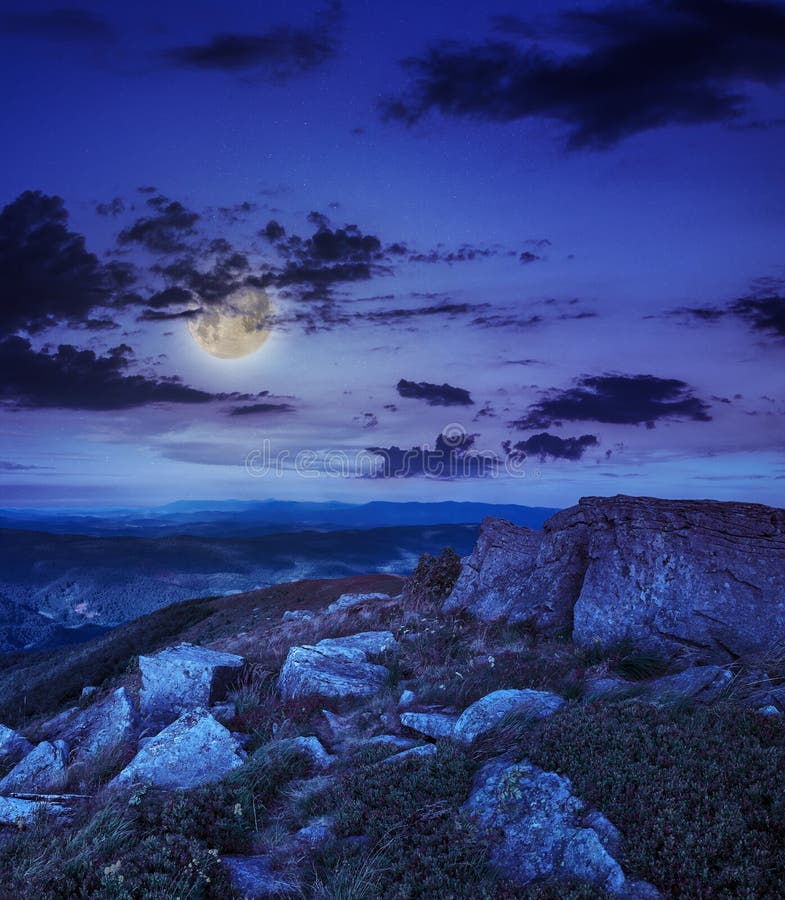 Light on stone mountain slope with forest at night