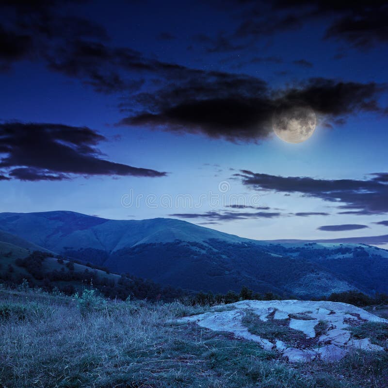 Light on stone mountain slope with forest at night