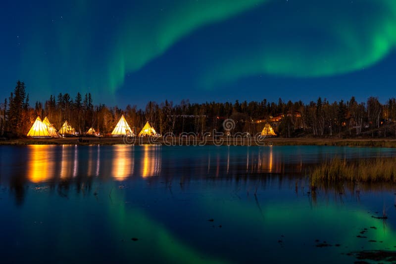 Light up Tipi & x28;indian Tent& x29; with water reflection during northern light in the sky
