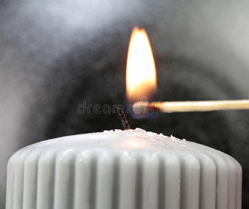 Light the wick of a candle with a match royalty free stock image