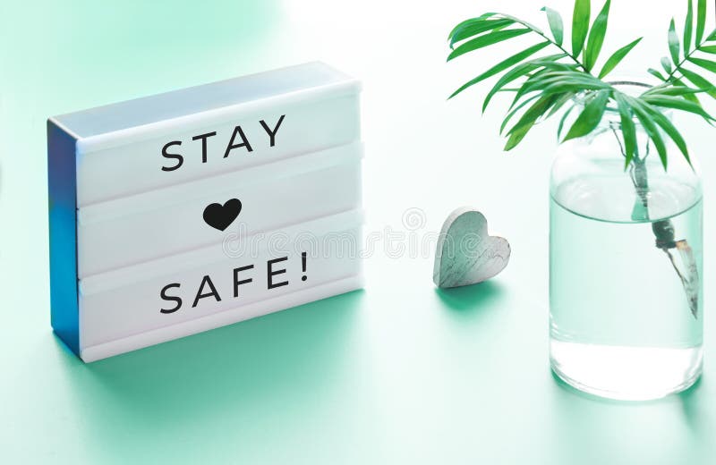 Lightbox with text. `Stay safe`, glass bottle with palm leaf and wooden heart. Wishing well to friends and family during quarantine and social distancing due to royalty free stock photography