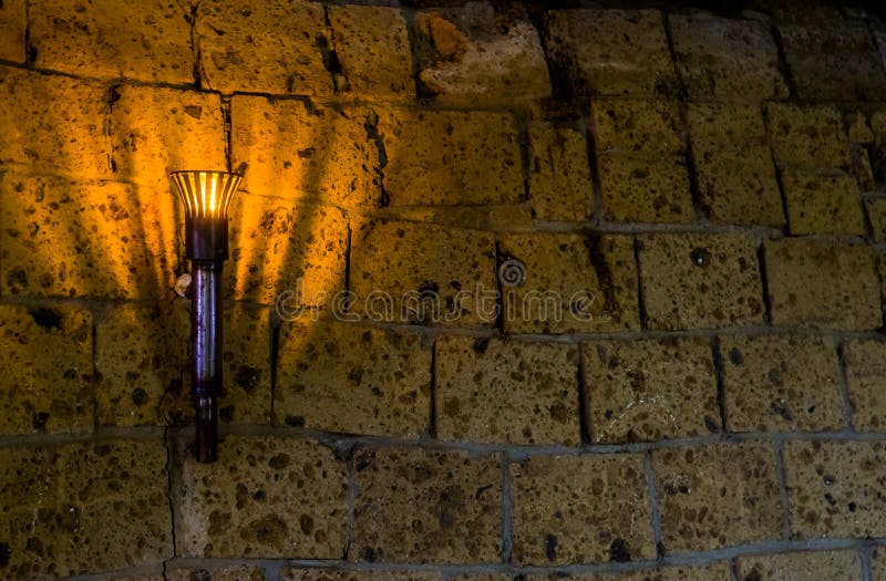 Lighted medieval castle torch hanging on a stone wall, vintage objects and background royalty free stock images Lighted medieval castle torch hanging on a stone wall, vintage objects and background royalty free stock images