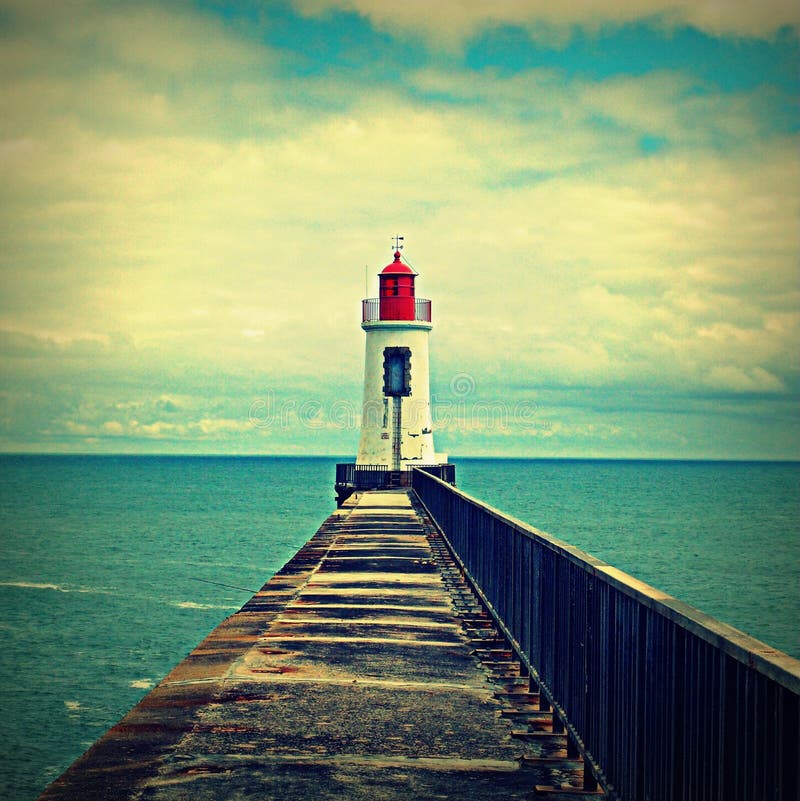 Lindo tradicional faro, de tarta sobre el el fin de oxidado muelle.