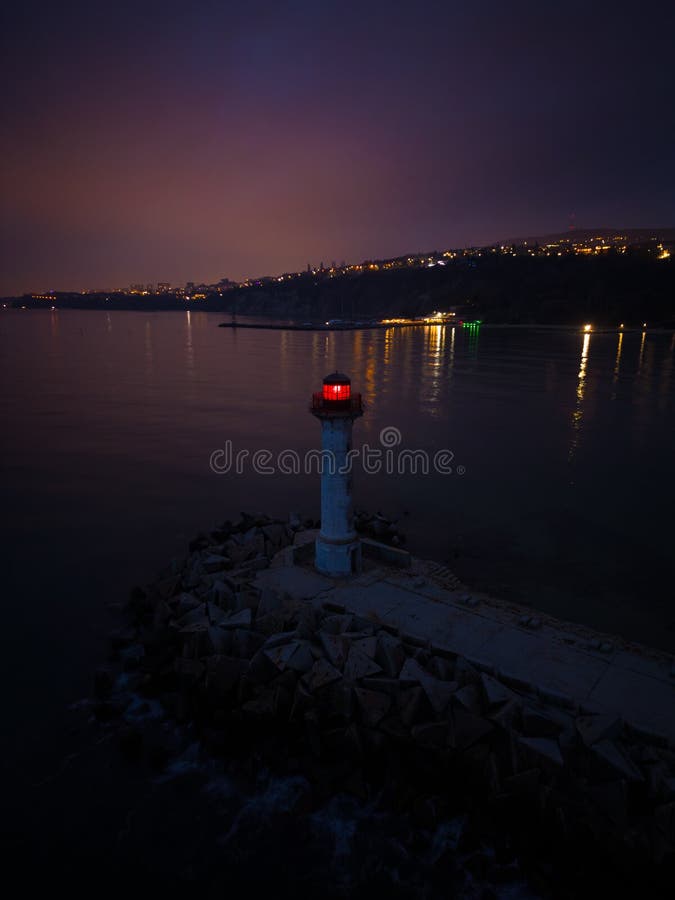 Lighthouse on the Seashore with Red Light at Night Against the