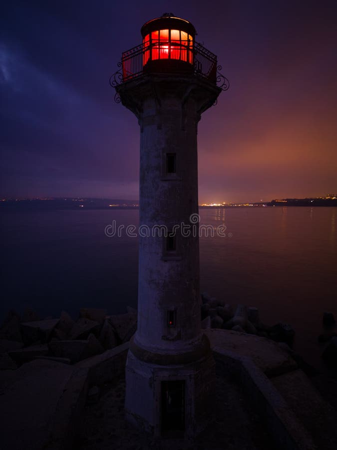 Lighthouse on the Seashore with Red Light at Night Against the