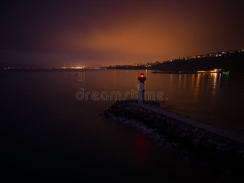 Lighthouse on the Seashore with Red Light at Night Against the