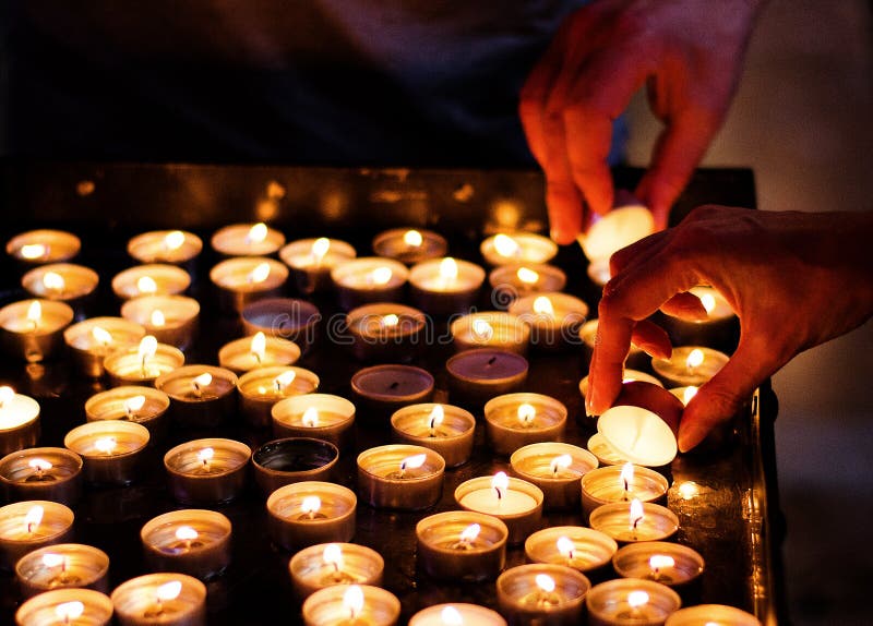 Žena strane osvetlenie sviečky v kostole s iným strane strácajú v pozadí.
