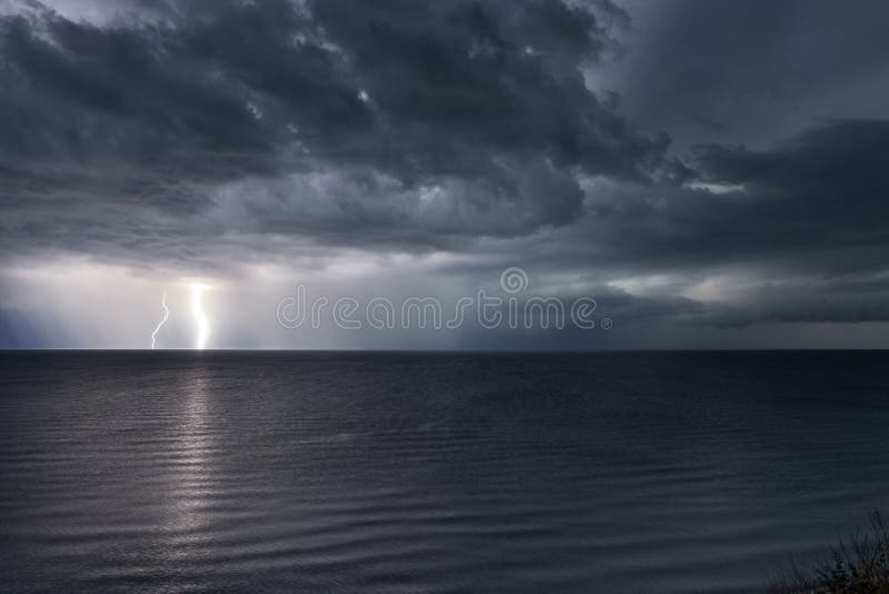 Lightning bolts reflection over the sea. taken during a thunderstorm over the ocean with clouds in the background stock photography