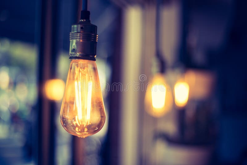 Lightning in the restaurant: Close up of a hanging, orange lightbulb royalty free stock photo