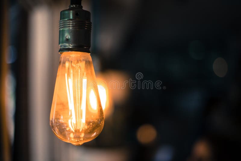 Lightning in the restaurant: Close up of a hanging, orange lightbulb royalty free stock image