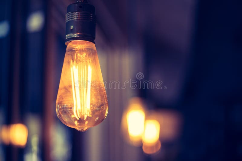 Lightning in the restaurant: Close up of a hanging, orange lightbulb royalty free stock image
