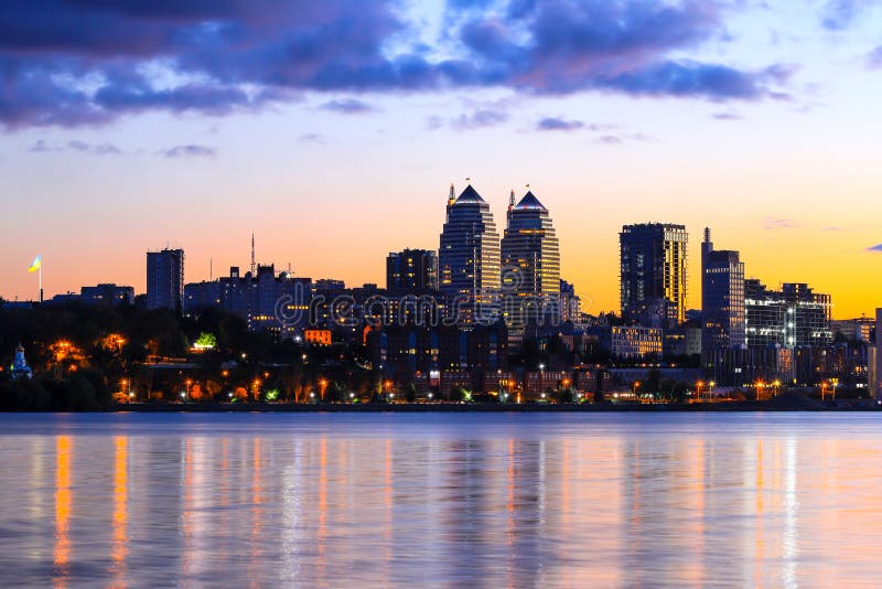 The lights of the Beautiful tall buildings, skyscrapers, towers are reflected in the Dnieper River at sunset in the evening. royalty free stock photos The lights of the Beautiful tall buildings, skyscrapers, towers are reflected in the Dnieper River at sunset in the evening. royalty free stock photos