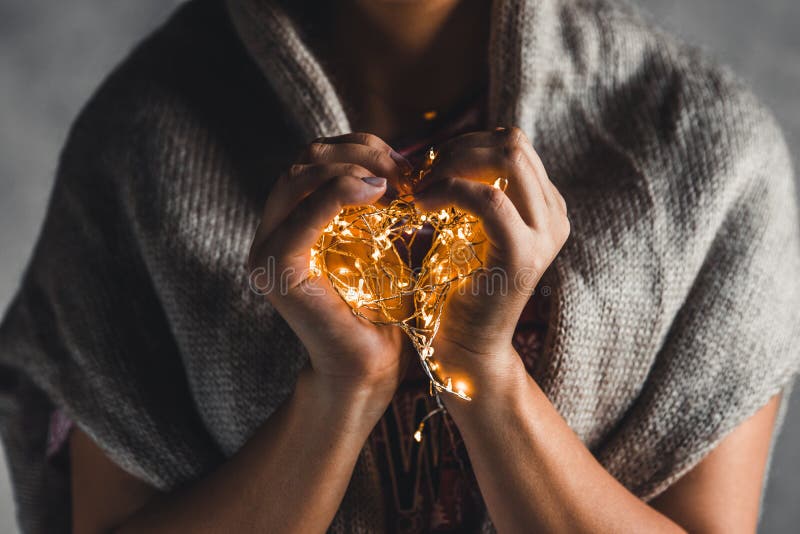 Lights in the palms. Women`s hands holding a garland. Girl in a red dress with Christmas lights