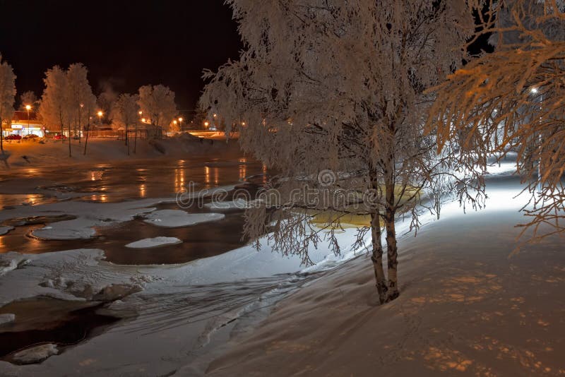 Night lights over the freezing river. The lights of the town reflect on the water of the freezing river Pyhajokin in the Northern Finland. The frost has coverd royalty free stock photography Night lights over the freezing river. The lights of the town reflect on the water of the freezing river Pyhajokin in the Northern Finland. The frost has coverd royalty free stock photography