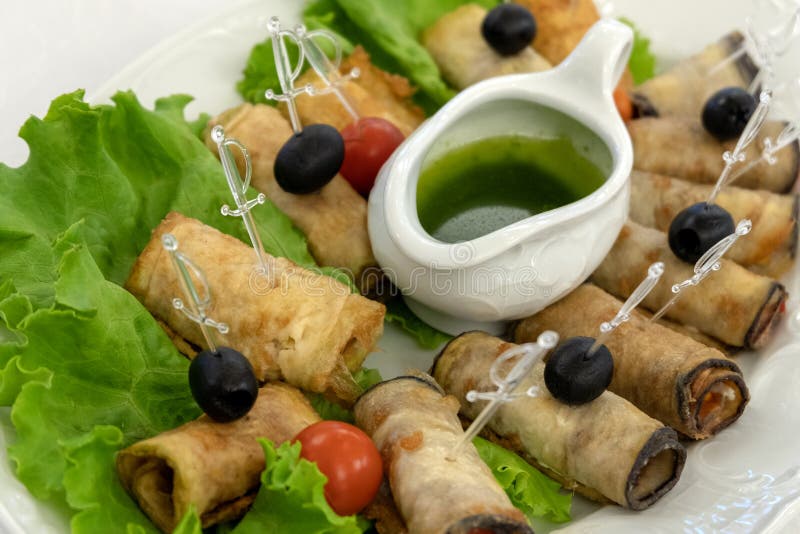 Lijst die in een restaurant plaatsen Koude snacks Gebraden courgettebroodjes met olijven en tomaten op slabladeren Groene saus en royalty-vrije stock foto's Lijst die in een restaurant plaatsen Koude snacks Gebraden courgettebroodjes met olijven en tomaten op slabladeren Groene saus en royalty-vrije stock foto's