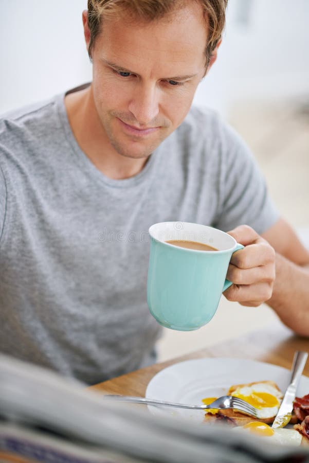 He Likes To Know Whats Going on in the World. a Handsome Man Reading the Paper while Having