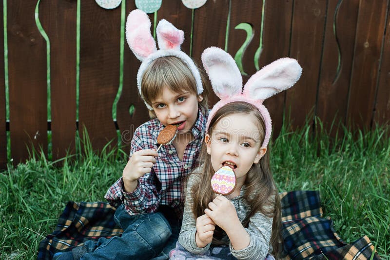 Lilla flickan och pojken äter en pepparkakakaka i formen av påskägget royaltyfri fotografi Lilla flickan och pojken äter en pepparkakakaka i formen av påskägget royaltyfri fotografi