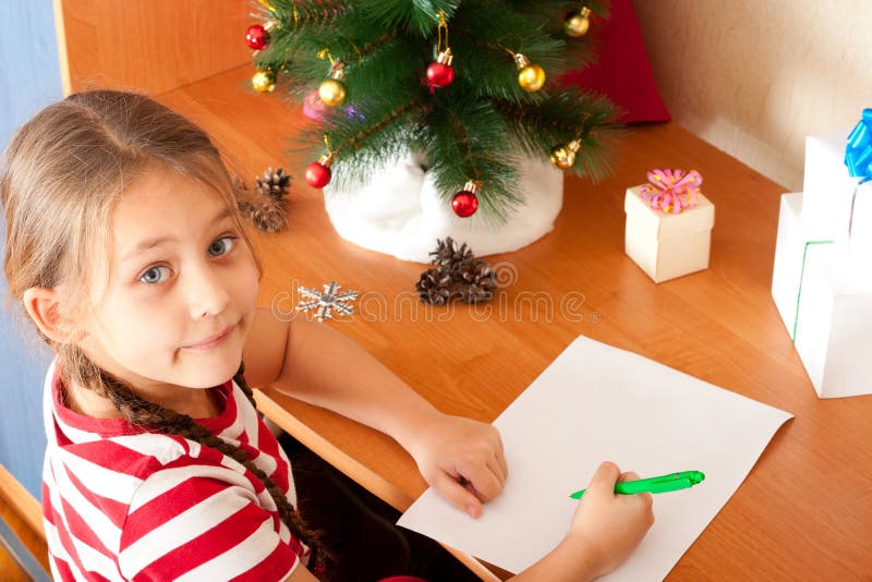 Lilla flickan skrivar ett brev till Santa Claus på vitbok royaltyfri bild Lilla flickan skrivar ett brev till Santa Claus på vitbok royaltyfri bild