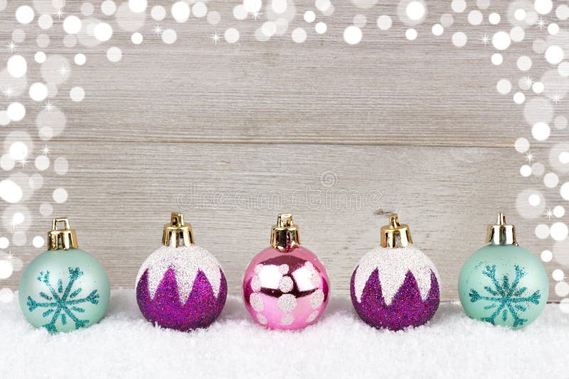Lilor, rosa färger och turkosjulstruntsaker i snö mot trä arkivfoto Lilor, rosa färger och turkosjulstruntsaker i snö mot trä arkivfoto