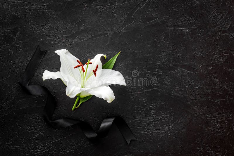 Lily funeral flower on dark stone. Condolence card with copy space