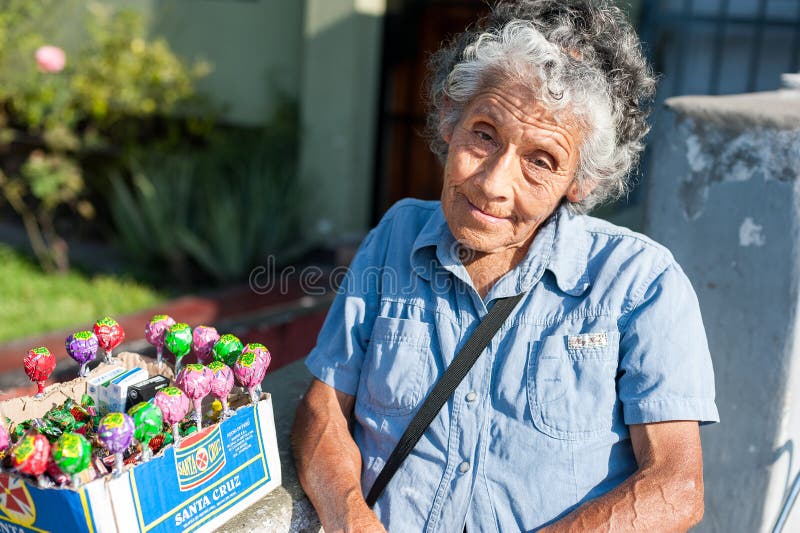 LIMA PERU - APRIL 12, 2013: En oidentifierad peruansk kvinna som säljer Chupa Chups sötsaker på gatan Isolerat på svart arkivfoton LIMA PERU - APRIL 12, 2013: En oidentifierad peruansk kvinna som säljer Chupa Chups sötsaker på gatan Isolerat på svart arkivfoton