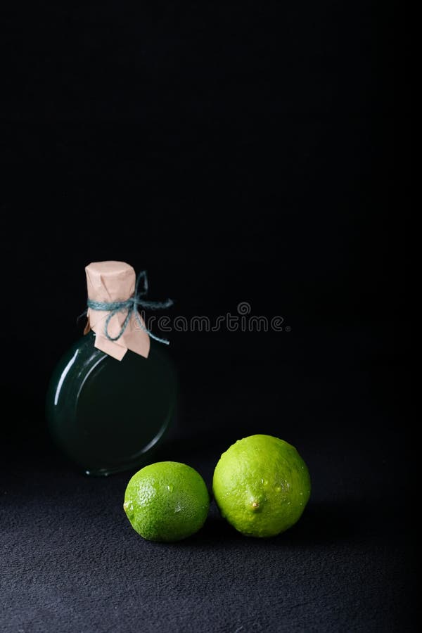 LIME ON A BLACK BACKGROUND WITH A BOTTLE OF LIME OIL royalty free stock photography LIME ON A BLACK BACKGROUND WITH A BOTTLE OF LIME OIL royalty free stock photography